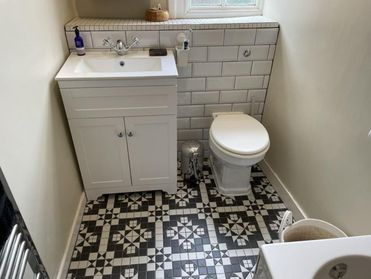 Picture of a white toilet and vanity unit installed by plumbers rotherham with retro style black pattern floor tiles